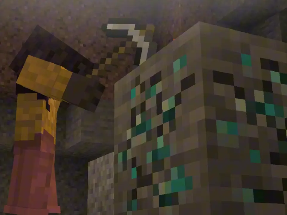 In a dim cave, a player raises a pickaxe over a block of ore.